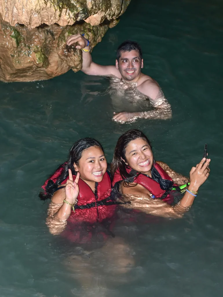 Grupo de 3 personas dos mujeres y un hombre sonrientes disfrutando de baño en Cenote en Punta Cana